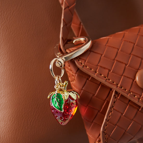 Roter Schlüsselanhänger in Erdbeerfom mit grünem Blatt und herzförmigen goldenen Karabiner.