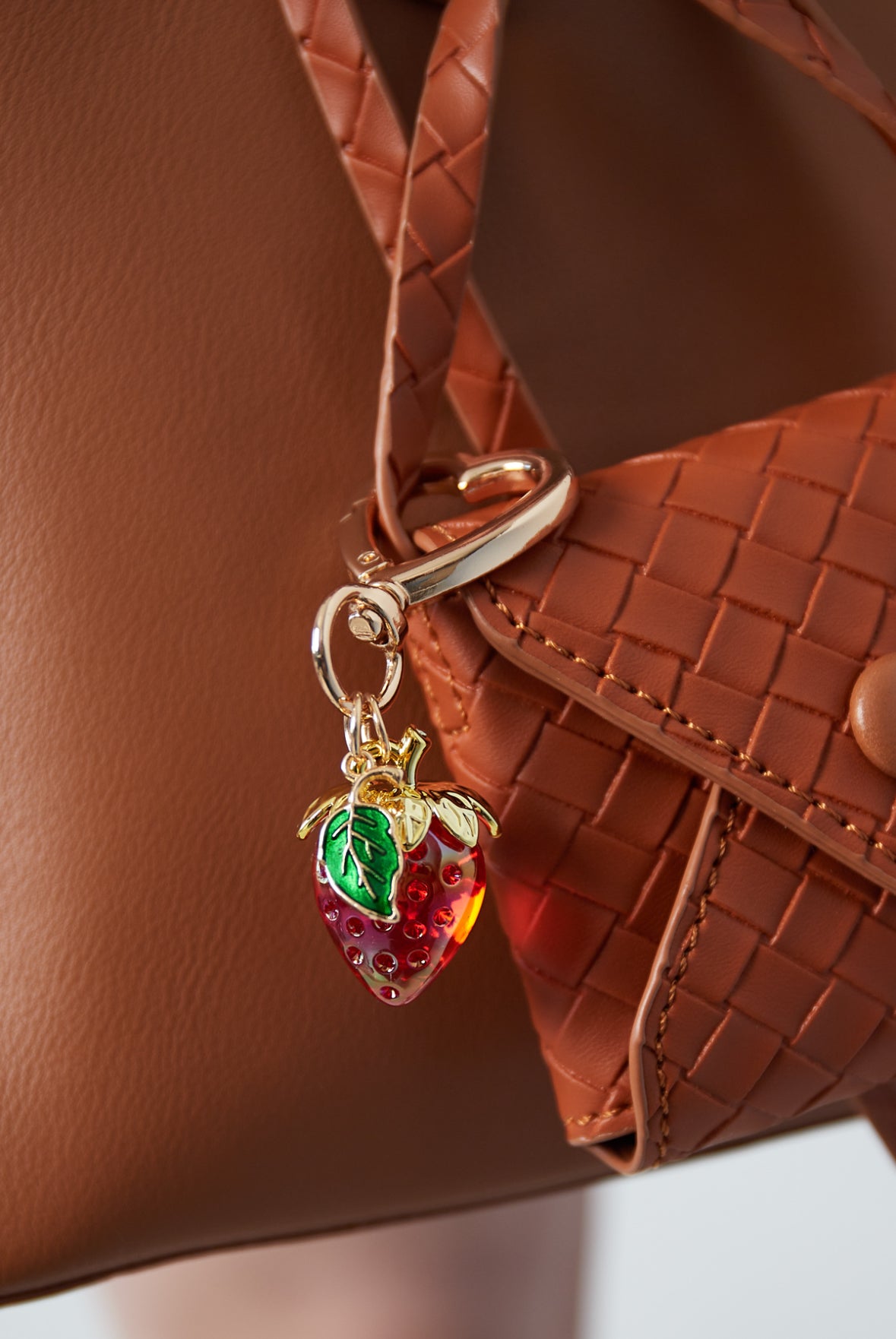 Roter Schlüsselanhänger in Erdbeerfom mit grünem Blatt und herzförmigen goldenen Karabiner.