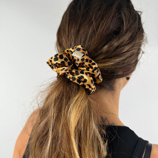 Profilansicht einer Frau mit Leo-Seiden-Scrunchie im Haar – eleganter und pflegender Look für den Alltag.