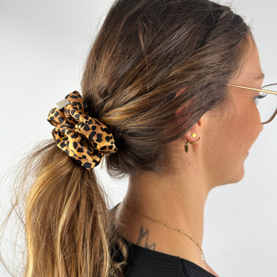 Scrunchie aus Leo-Seide im Haar, gebunden zu einem tiefen Zopf – edler Glanz und weiche Textur.