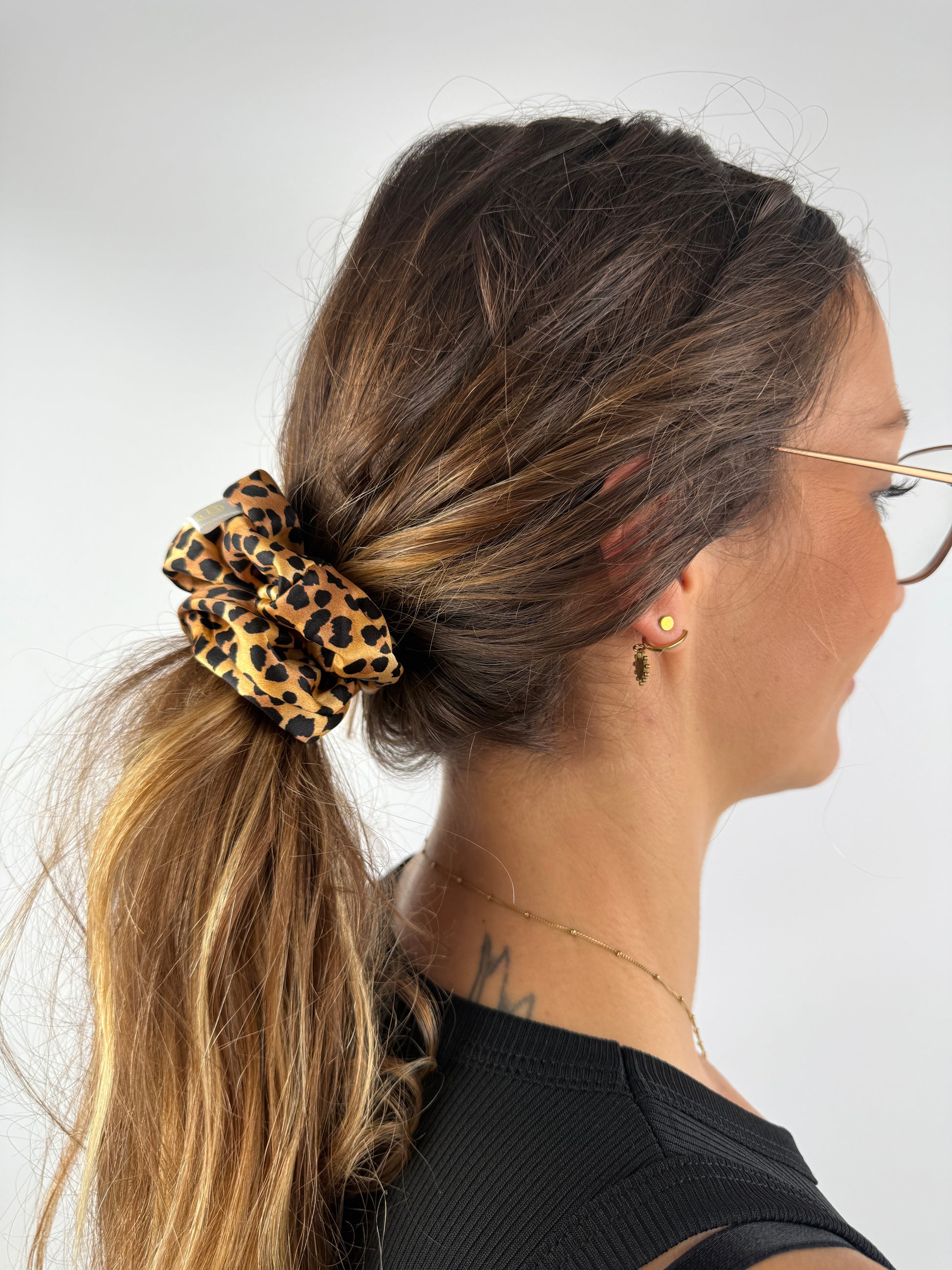 Scrunchie aus Leo-Seide im Haar, gebunden zu einem tiefen Zopf – edler Glanz und weiche Textur.