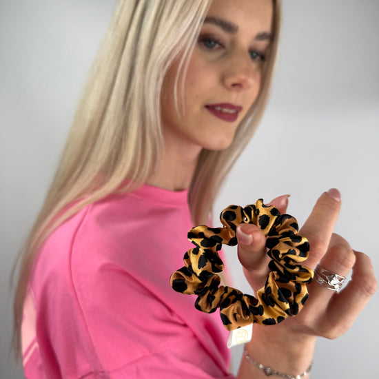 Nahaufnahme eines Seiden-Scrunchies mit Leopardmuster.