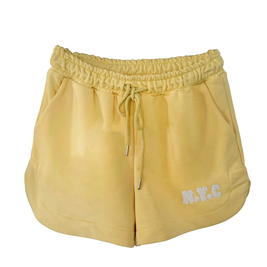 Kurze gelbe Baumwollshorts mit flauschiger N.Y.C Aufschrift, seitlichen Taschen und Kordel im Gummibund.