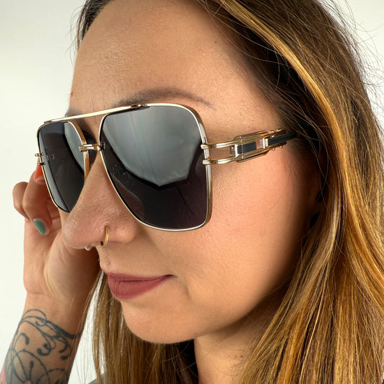 Sonnenbrille mit feinem goldenem GEstell und schwarzen Gläsern.