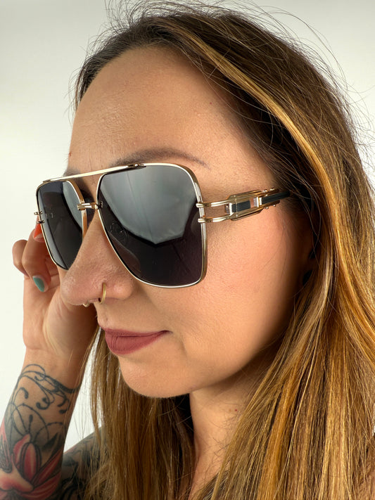 Sonnenbrille mit feinem goldenem GEstell und schwarzen Gläsern.