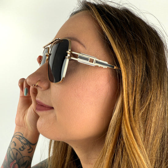 Sonnenbrille mit feinem goldenem GEstell und schwarzen Gläsern.