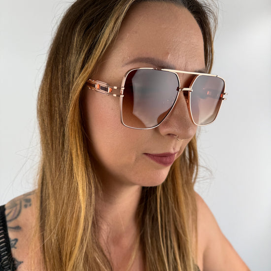 Sonnenbrille mit Braunen nach unten heller werdenden Gläsern und rose Goldenem Gestell.