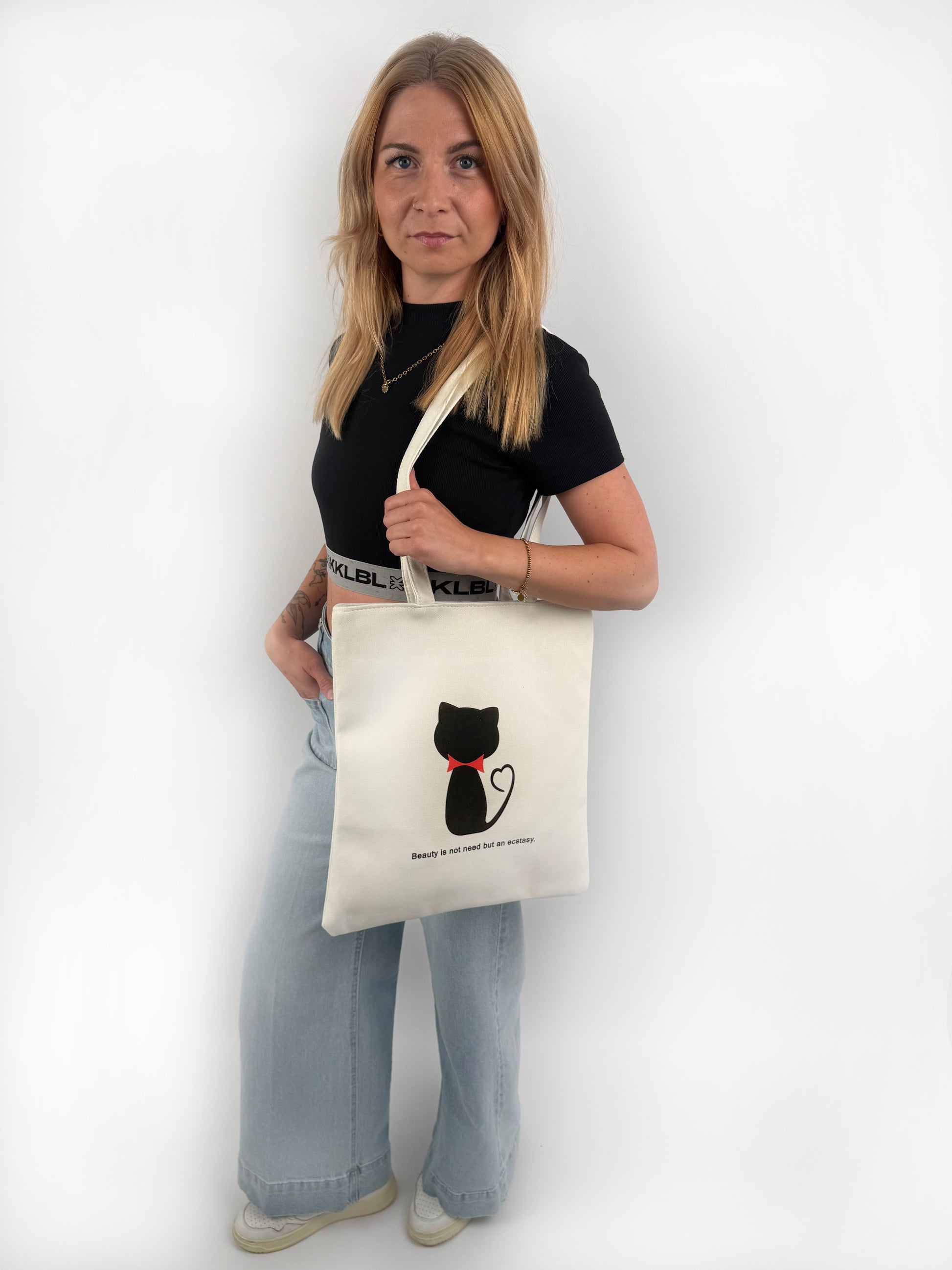 Weißer Stoffbeutel mit schwarzer Katze mit roter Schleife um den Hals auf der Vorderseite.