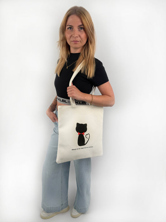 Weißer Stoffbeutel mit schwarzer Katze mit roter Schleife um den Hals auf der Vorderseite.