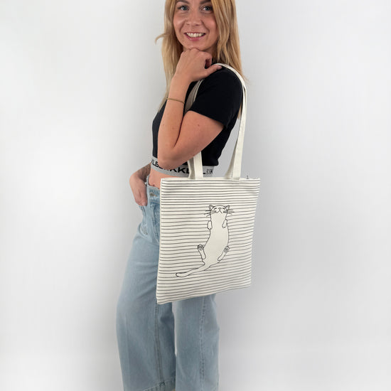 Weißer Stoffbeutel mit schwarzer Katze und dünnen schwarzen Streifen auf der Vorderseite.