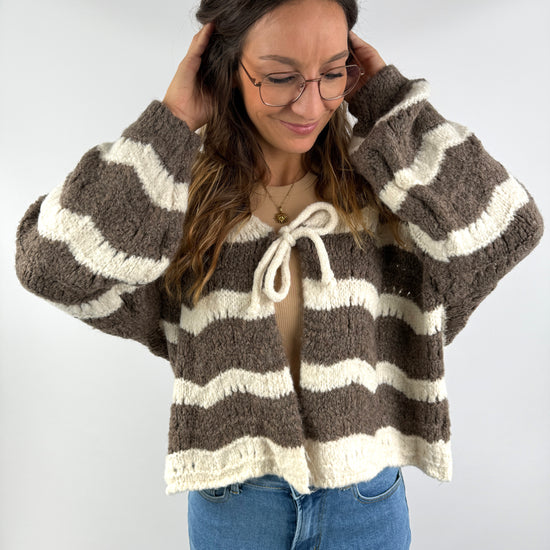 Braun-creme gestreifte Strickjacke mit Schleife vorne, kombiniert mit Jeans und beigem Top – lässig, weich und cozy gestylt.