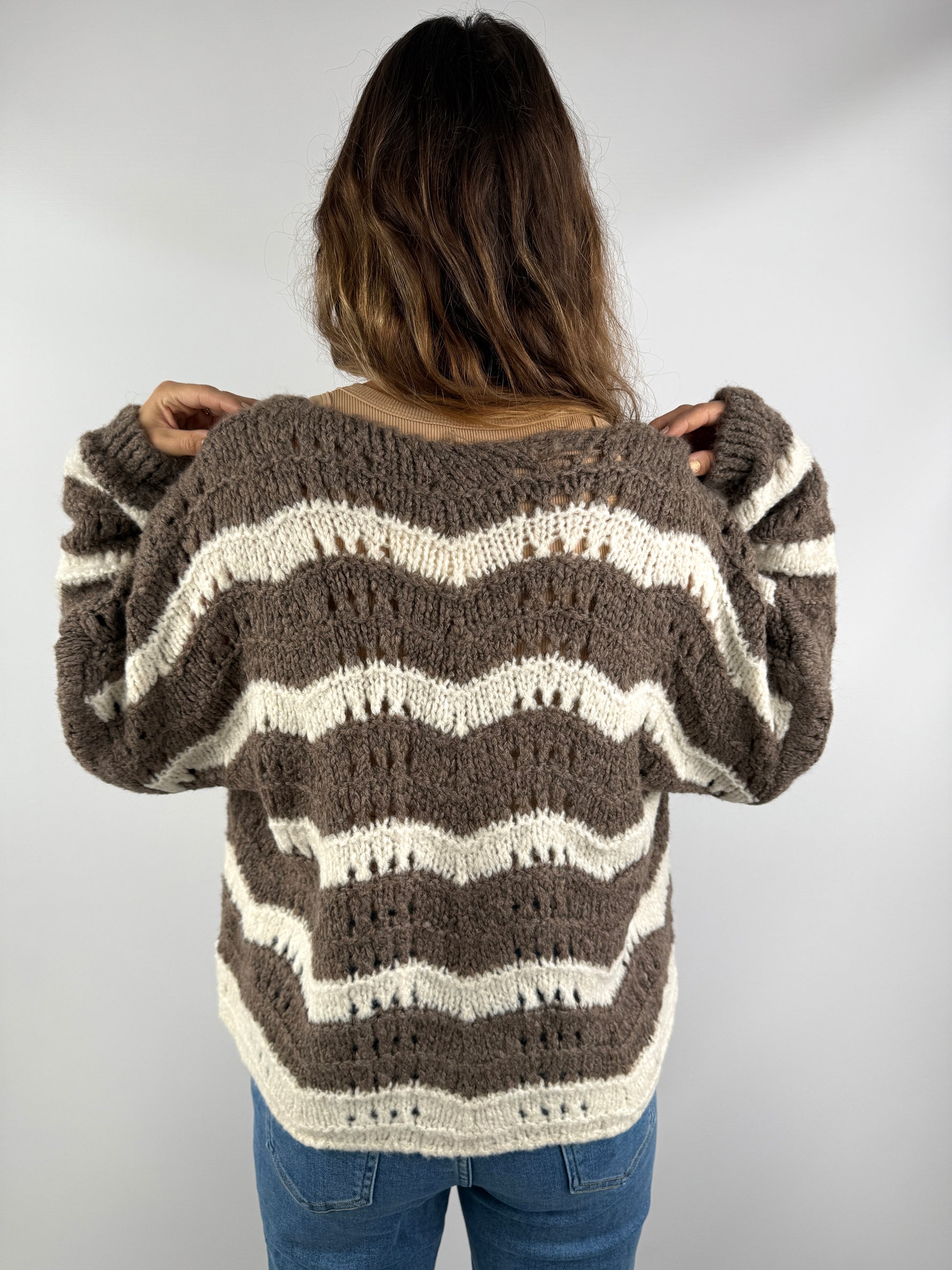 Rückenansicht einer braun-cremefarbenen Strickjacke mit wellenförmigem Streifenmuster – locker geschnitten und weich fallend.
