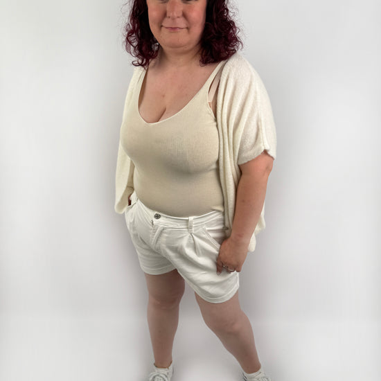 Wollweste in seichten farben mit kurzen Ärmeln und hellen größeren Knöpfen an der Vorderseite.