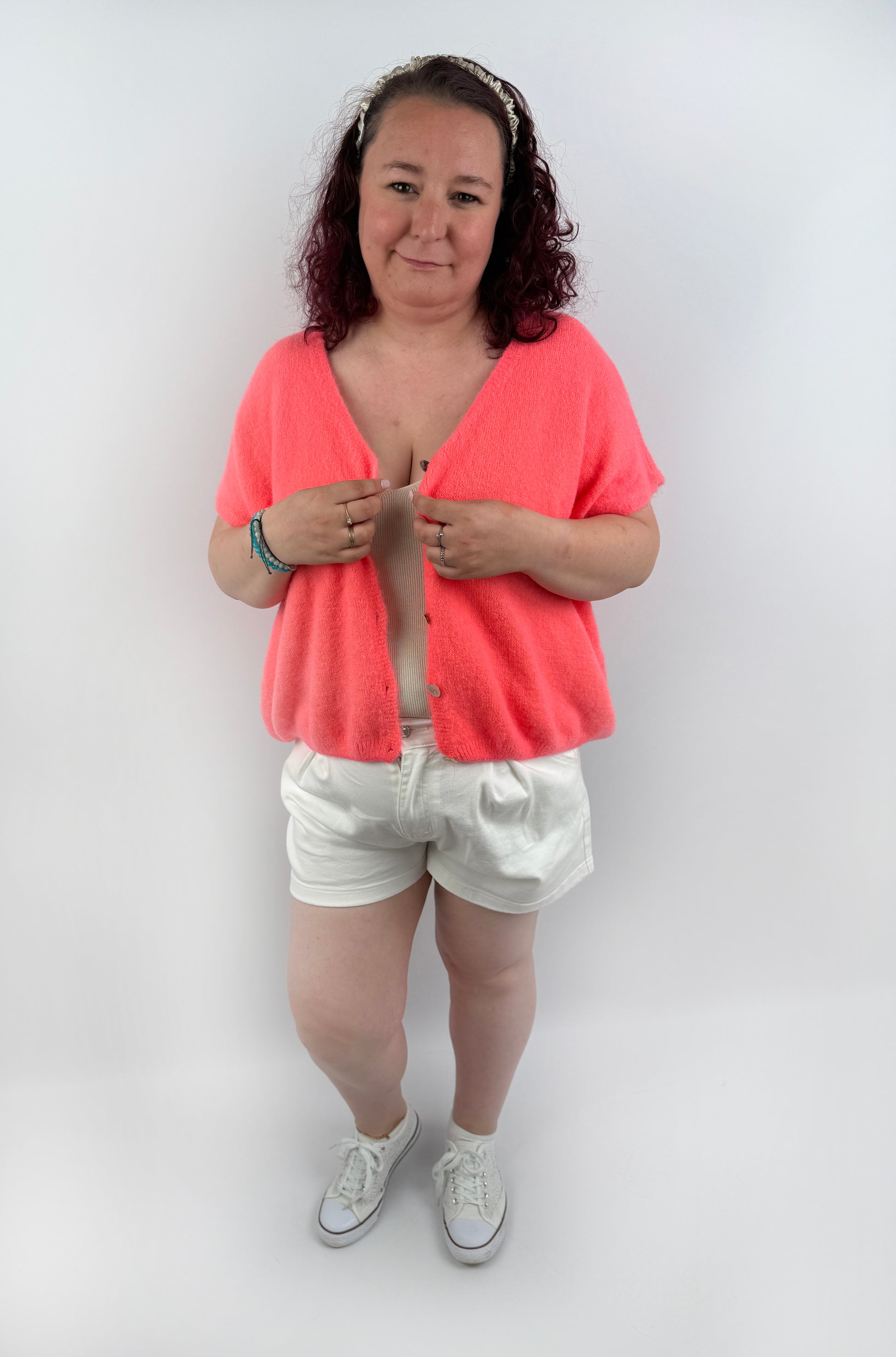 Wollweste in seichten farben mit kurzen Ärmeln und hellen größeren Knöpfen an der Vorderseite.