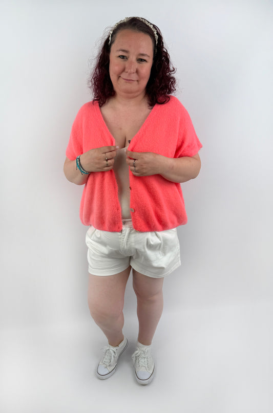 Wollweste in seichten farben mit kurzen Ärmeln und hellen größeren Knöpfen an der Vorderseite.