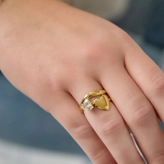 Goldener, verstellbarer Ring mit Herz und Kristall an einer Hand getragen 